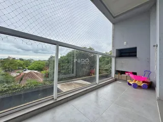 Vista de uma varanda com piso de concreto e grade de vidro em Lajeado, Brasil.
