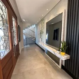 Vista de um corredor interno com piso claro e escadaria ao fundo.