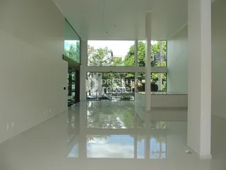 Espaço interno amplo com paredes brancas e grande janela de vidro.