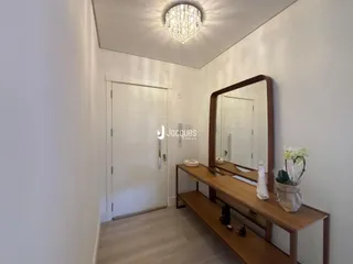 Vista do corredor interno de uma residência com paredes brancas e piso de madeira clara.