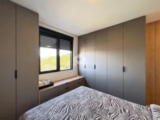 Quarto com armários embutidos e janela de vista para a vegetação.