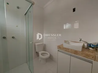 Foto de um banheiro com box de vidro e louças brancas.