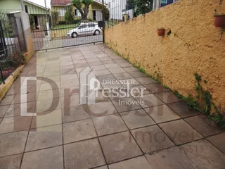 Pátio externo com piso de concreto ao lado de uma parede amarelada.