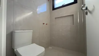 Foto de um banheiro com revestimento de azulejos brancos e um vaso sanitário.