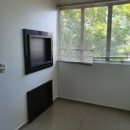 Foto interna de uma sala com janela e televisão.
