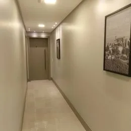 Corredor interno com paredes claras e piso claro.