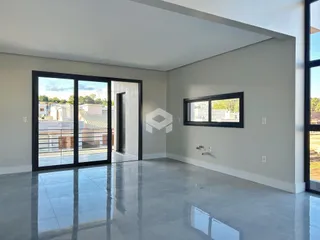 Ambiente interno de uma sala com piso de concreto polido e portas de vidro grandes.