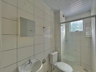 A foto mostra o interior de um banheiro com revestimento cerâmico branco.