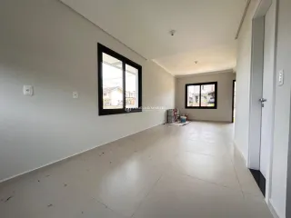 Vista interna de um ambiente amplo com paredes brancas e uma grande janela.