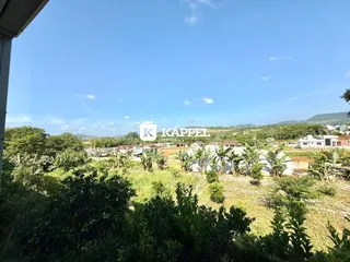 Vista panorâmica de paisagem com vegetação exuberante e colinas ao fundo.