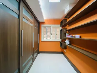 Interior de um ambiente com paredes laranjas e piso branco e armários em madeira.