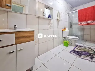 Foto de um banheiro com revestimento de azulejos brancos e bancada de madeira.