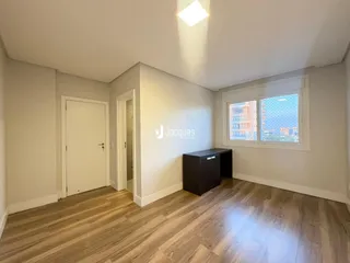Ambiente interno de uma sala com piso de madeira clara e janela.