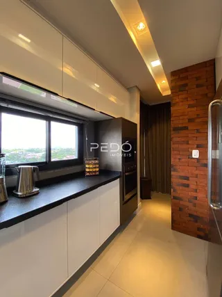 Cozinha moderna com armários brancos e parede de tijolos aparentes.
