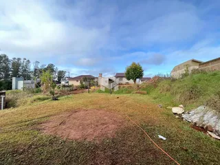 Vista externa de um terreno gramado com vegetação ao fundo.