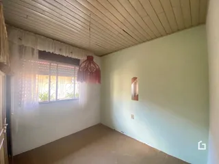 Interior de uma sala com teto de madeira e parede clara.