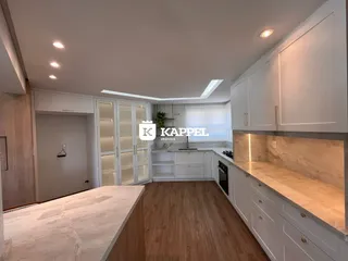 Cozinha moderna com armários brancos e piso de madeira clara.