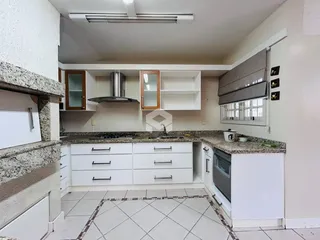 A cozinha apresenta armários brancos e piso cerâmico.
