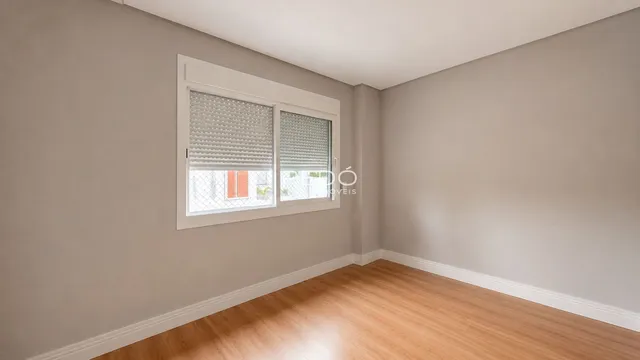Ambiente interno de uma sala com piso de madeira clara e janela.