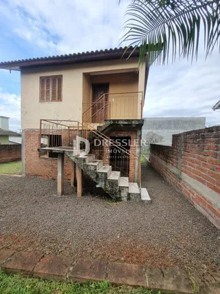 Fachada de uma residência com escadaria externa e muro de tijolos.