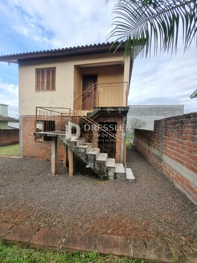 Fachada de uma residência com escadaria externa e muro de tijolos.