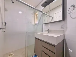 Banheiro moderno com box de vidro e bancada de mármore.