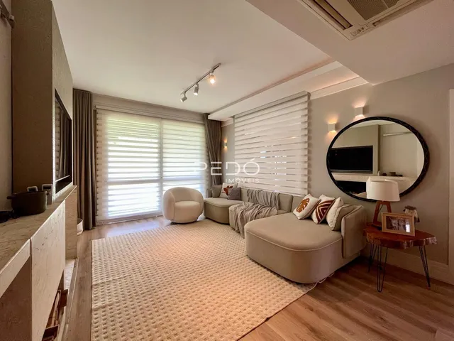 Sala de estar com piso de madeira e grande janela iluminada.