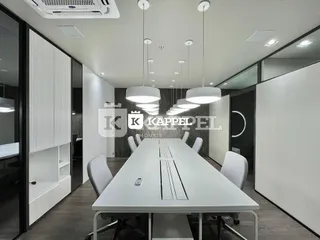 Foto de um ambiente interno com uma mesa longa e cadeiras brancas.