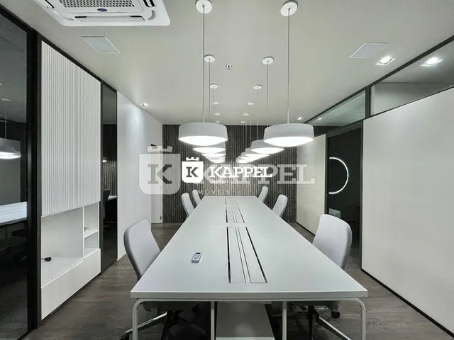 Foto de um ambiente interno com uma mesa longa e cadeiras brancas.