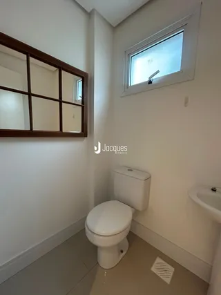 Vista interna de um banheiro com paredes brancas e piso claro.