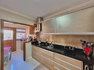 Vista da cozinha com armários e bancadas em madeira e granito.
