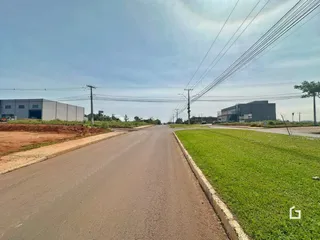 Vista externa de uma rua com gramado e edifícios ao fundo.