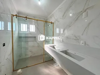 Cozinha moderna com bancadas brancas e paredes de mármore claro.