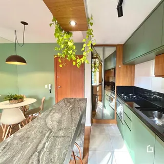 Ambiente de sala de jantar e cozinha com paredes verde-água e bancada de mármore.