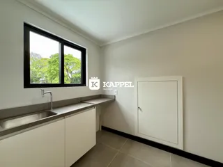 A foto mostra uma bancada com pia e uma janela com vista para a natureza.
