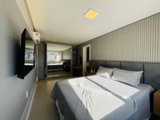 Quarto com cama grande e parede de espelho em um imóvel no Brasil.