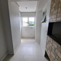 Corredor interno com paredes brancas e janela no final.