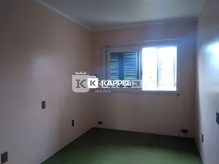 Foto interna de um cômodo com paredes rosadas e piso de carpete.