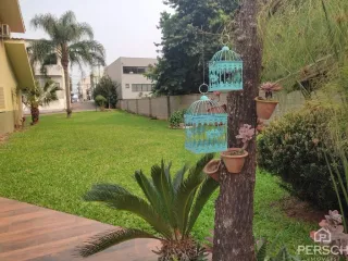 Jardim com gramado e árvores em uma área externa da propriedade.