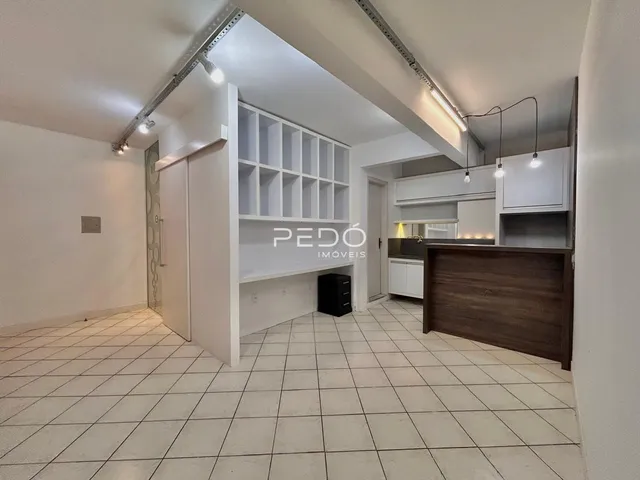 Sala de estar com piso de cerâmica e estantes brancas em um imóvel no Brasil.