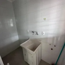 Foto de um banheiro com pia branca e revestimento de azulejos brancos.