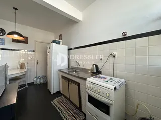 Foto de uma cozinha com revestimento de azulejo branco e piso escuro.