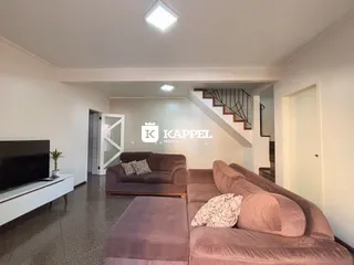 Sala de estar com sofá grande e televisão em ambiente claro.