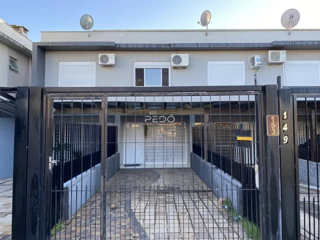 Fachada de um imóvel residencial com portão de ferro na entrada.