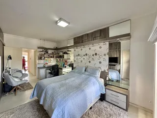 Quarto com cama grande e cabeceira de madeira em um apartamento no Brasil.