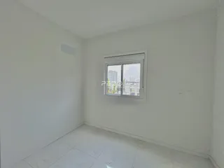 Ambiente interno de uma sala com paredes brancas e piso de cerâmica.