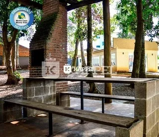 Foto de uma área externa com bancos de pedra e estrutura de tijolos.