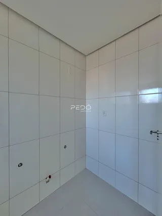Hall de entrada com revestimento cerâmico branco e piso cinza claro.