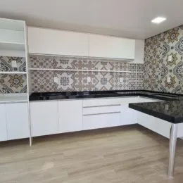 Foto de uma cozinha com armários brancos e bancada escura.