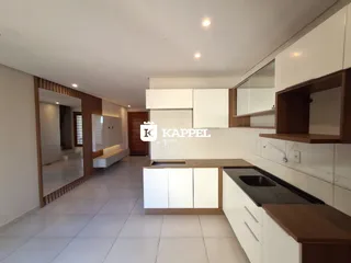 Cozinha moderna com armários brancos e bancada escura em um ambiente claro.